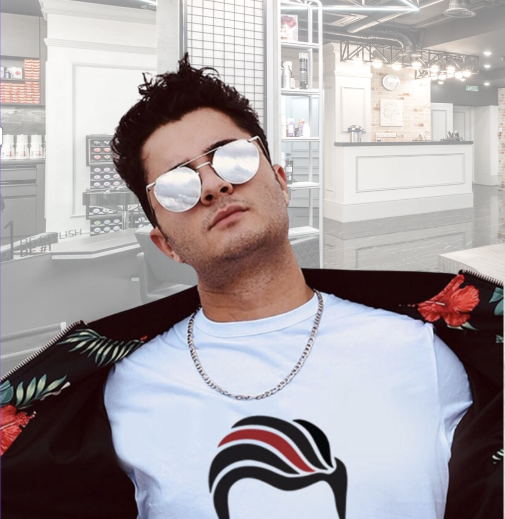 “Man with short dark hair wearing reflective sunglasses, a white shirt, and a chain necklace, posing confidently in a modern salon setting.”