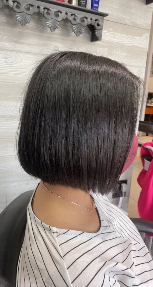 “Chin-length sleek black bob haircut with a smooth, shiny finish, photographed in a salon setting.”