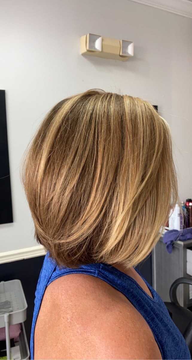 “Shoulder-length layered bob with blonde highlights and a smooth, voluminous finish, styled elegantly in a salon.”