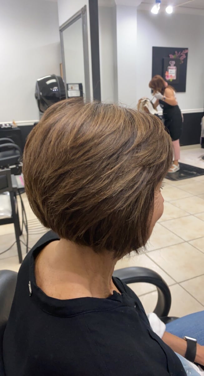 “Chin-length layered bob hairstyle with soft brown tones and subtle highlights, styled with volume, photographed in a salon.”